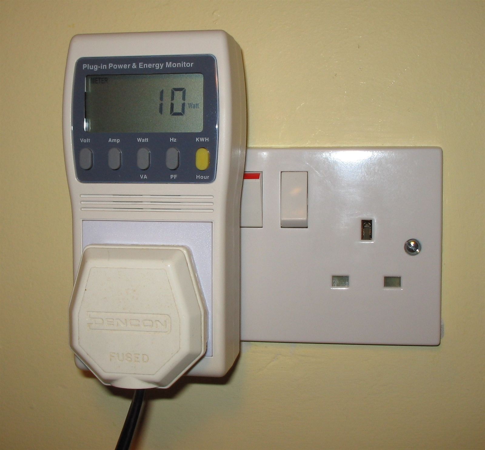 A plug-in energy monitor in a UK wall socket showing power use